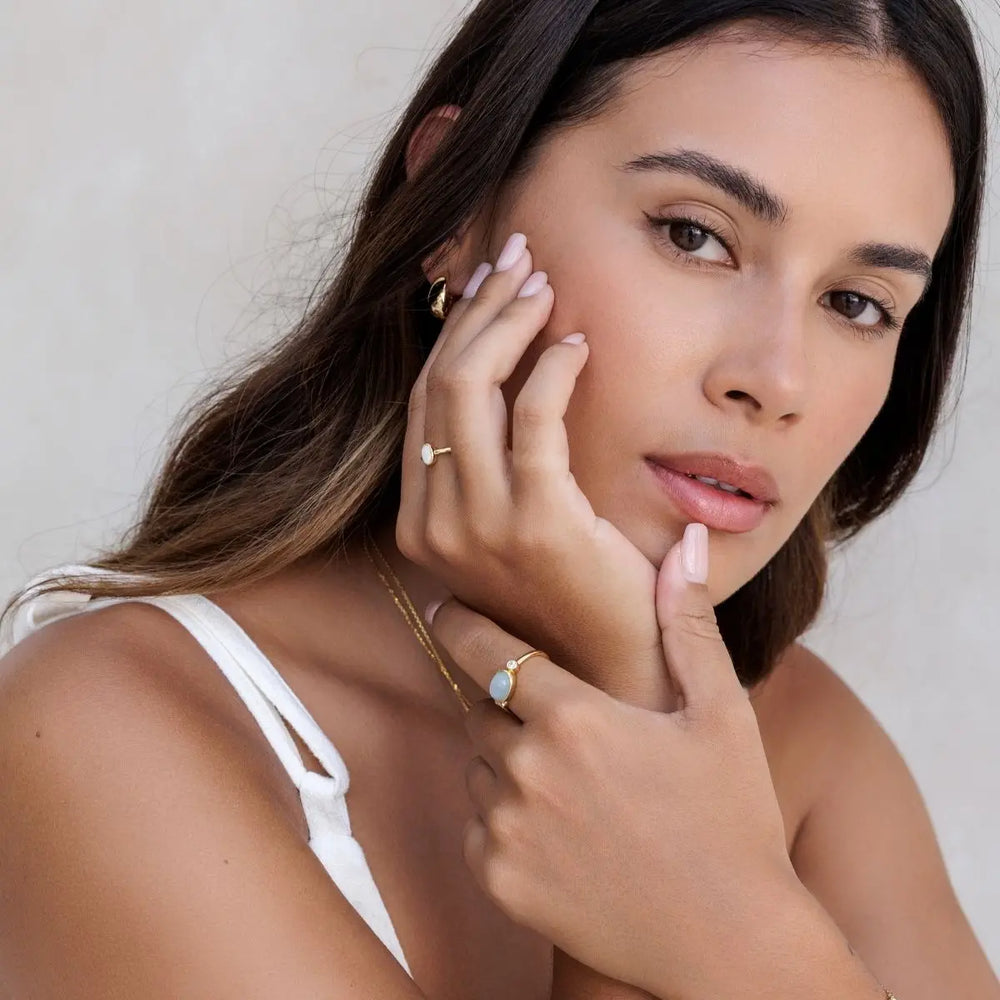 Woman wearing gold jewelry against a neutral background