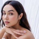 Woman wearing gold jewelry against a white background