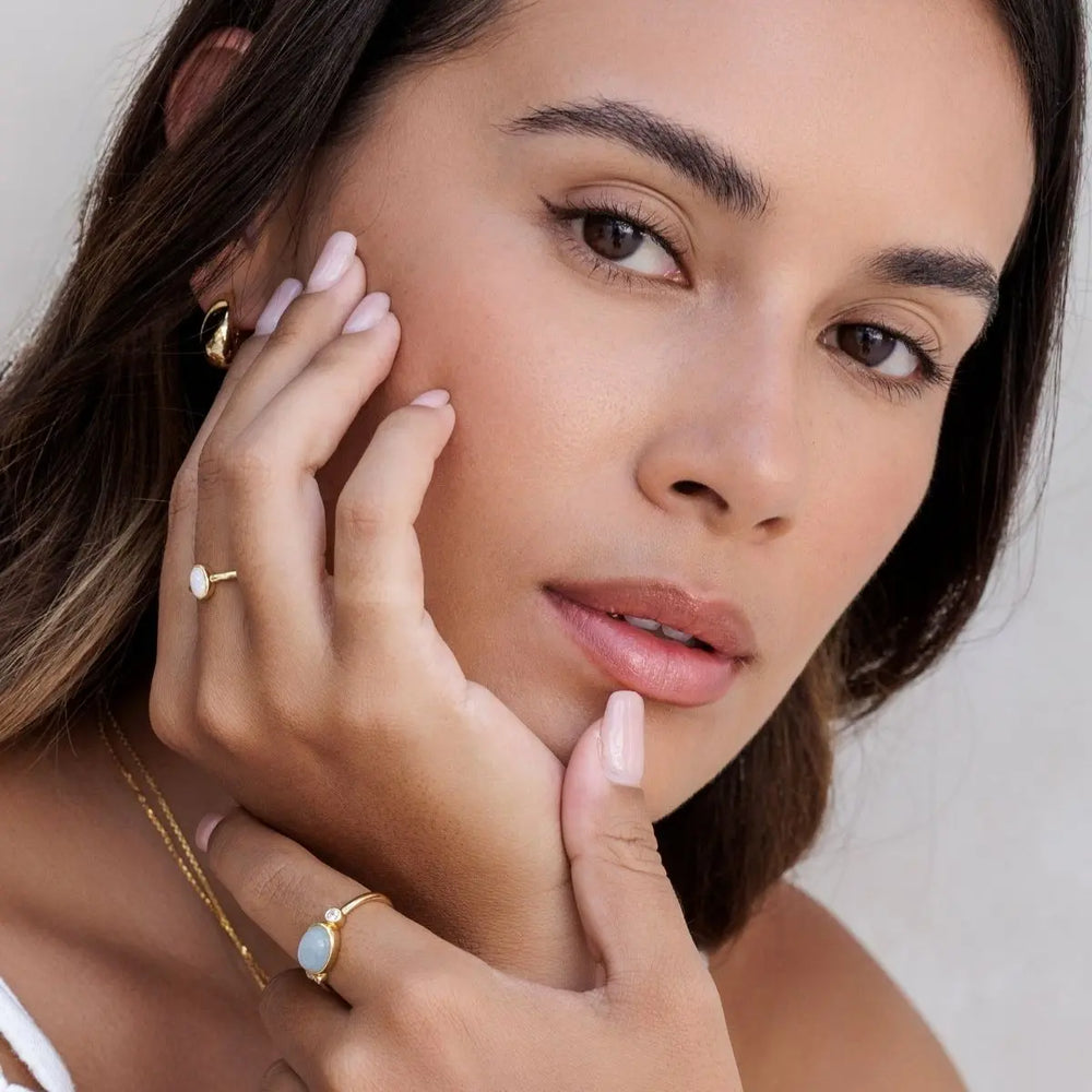 Woman wearing gold jewelry with a neutral background